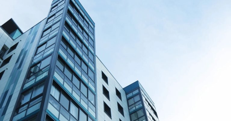 Modern commercial building with reflective glass facade under blue sky