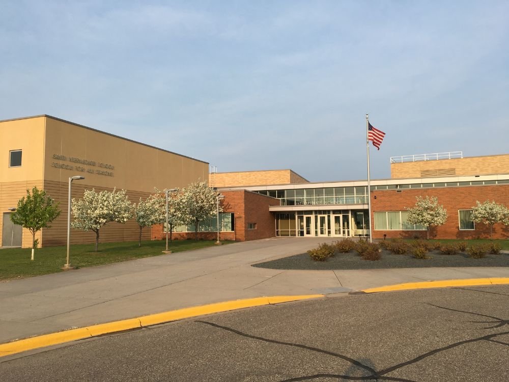 Exterior view of a public school building with American flag and flowering trees
