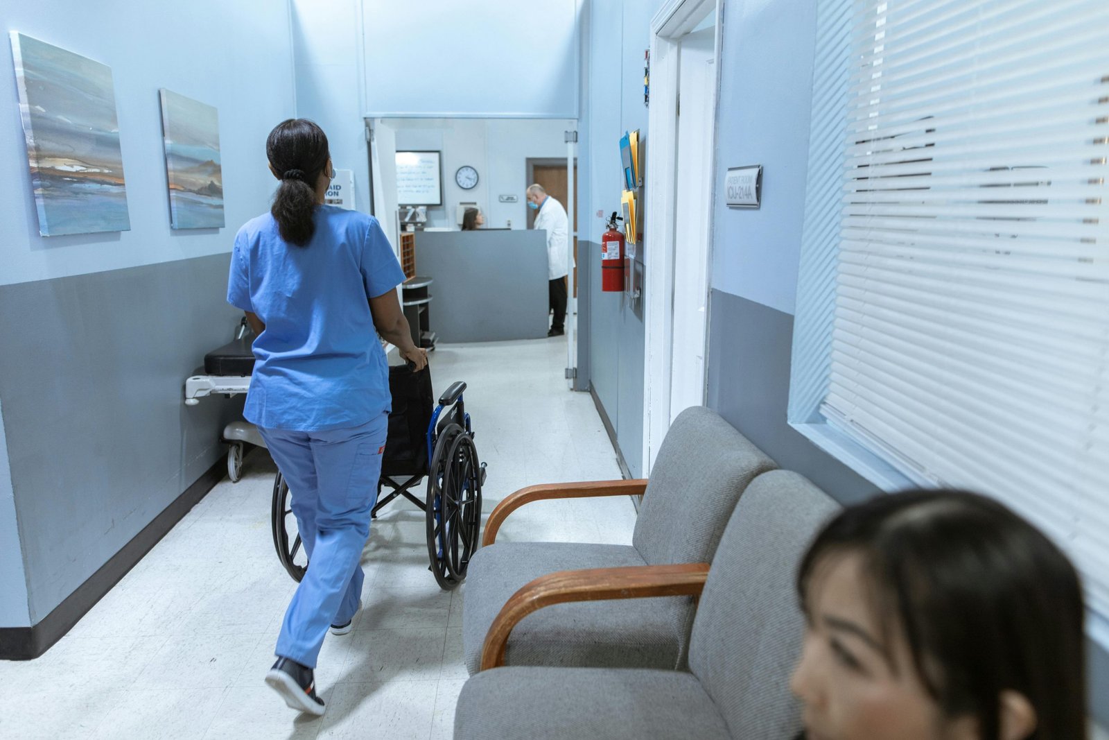 Nurse pushing wheelchair through medical clinic hallway