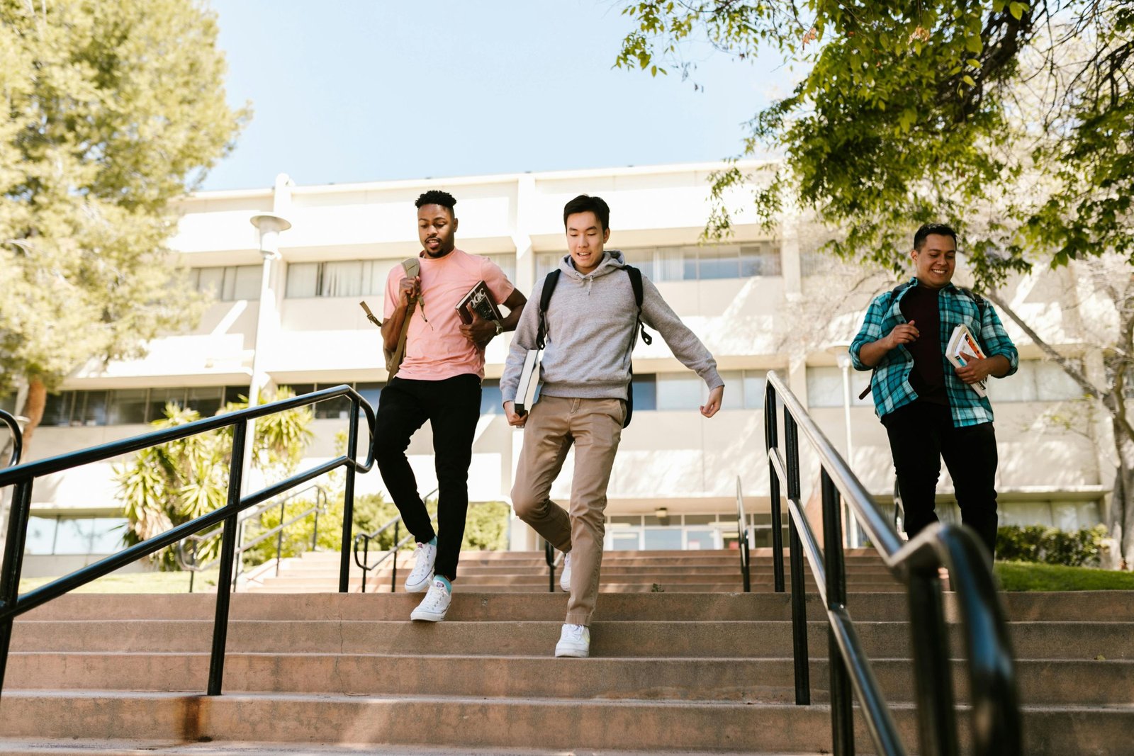 Students walking down steps outside a modern school or university campus building
